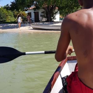 un hombre remando en un bote con una paleta en el agua en Casa Bela do Sol, en Isla de Boipeba