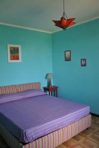 una camera con letto viola e parete blu di B&B La vecchia quercia Home Restaurant a Fornovo di Taro