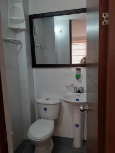 a bathroom with a toilet and a sink and a mirror at Habitaciones Altos de Cooservicios in Tunja