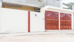 una recinzione bianca con un cancello rosso di fronte a un edificio di Appartement F4 Climatisé RDC à Totsi près de la maison ADEBAYOR a Lomé