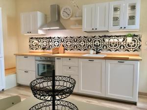 a kitchen with white cabinets and a black and white wallpaper at Alessia House in Bagnoregio