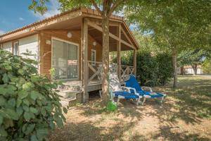 a cabin with two blue chairs in front of it at Camping Le Méditerranée Argelès - Domaine piétonnier in Argelès-sur-Mer