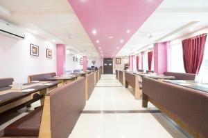 ein Restaurant mit Holztischen und -stühlen und rosa Wänden in der Unterkunft Nakshatra Hotel in Bānswāra