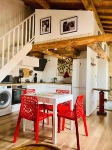 cocina con mesa blanca y sillas rojas en Lou Mirèio, en Aigues-Mortes