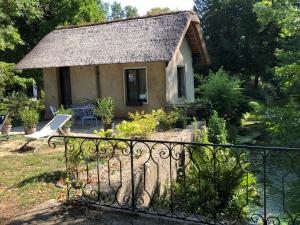 a small house with a thatched roof in a garden at Chaumière au bord de l'eau - Domaine de 3 hectares - Borne Electrique - Chiens acceptés in Hondouville +11 photos
