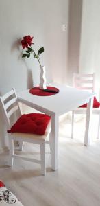 a white table and two chairs with a vase with a flower at Colourful Rooms Wrocław in Wrocław