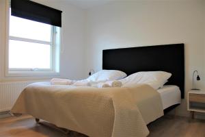 a bedroom with a bed with a black headboard and a window at Hotel Nuka in Ilulissat