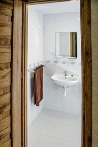a white bathroom with a sink and a mirror at Everena Guest House in Rokiškis