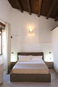 a bed in a bedroom with a white wall at Italiana Resort Atrio in Siracusa