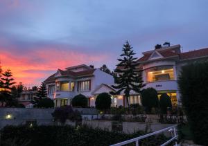 a house with a tree in front of a sunset at Twin Tree in Kotagiri
