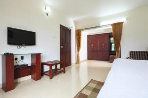 a bedroom with a bed and a flat screen tv at Twin Tree in Kotagiri