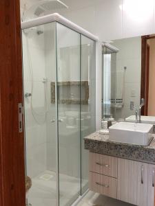 a bathroom with a glass shower and a sink at Apartamento Luxuoso com Vista in Ilhéus