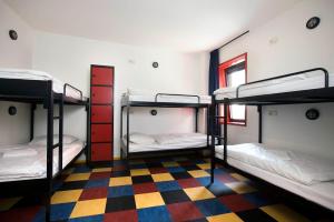 a dorm room with three bunk beds and a checkered floor at Bud Gett Hostels in Groningen