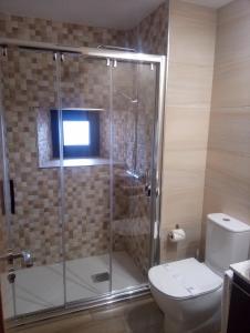 a bathroom with a glass shower with a toilet at Valle del sol I in Pajares