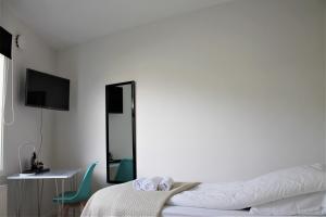 a white bedroom with a bed and a mirror at Hotel Nuka in Ilulissat