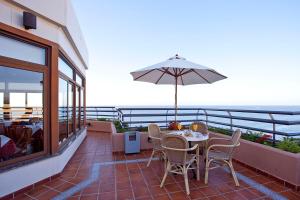 een patio met een tafel en stoelen en een parasol bij Hotel Apartamentos Princesa Playa in Marbella