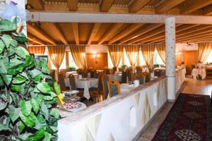 a restaurant with tables and chairs and plants at Hotel Relais Grünwald in Cavalese