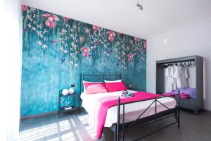 a bedroom with a bed and a blue wall with pink flowers at BOTANIKA in Bologna