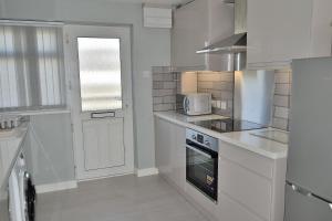 Biała kuchnia z kuchenką mikrofalową i kuchenką w obiekcie 2 Rosemullion w mieście Perranporth