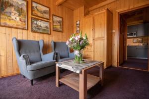 a living room with two chairs and a vase of flowers on a table at Willa Regionalna Kosołka in Zakopane