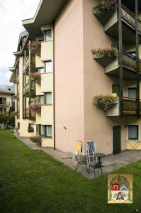 a building with two chairs and a table in front of it at Residenza Artini in Comano Terme