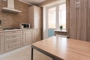 a kitchen with white cabinets and a wooden table at Luxury apart-hotel on Kharkovskaya neer Manufaktura in Sumy