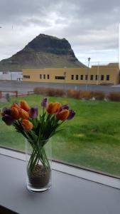 un jarrón de flores sentado en un alféizar de la ventana en Guesthouse 43, en Grundarfjordur