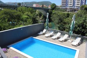 a swimming pool with lounge chairs and a bridge at Apartments Aldi in Mostar