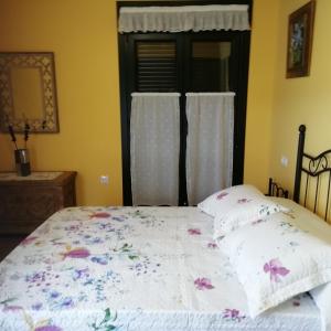 a bedroom with a bed with a floral comforter and a window at A Fragua in Tapia de Casariego