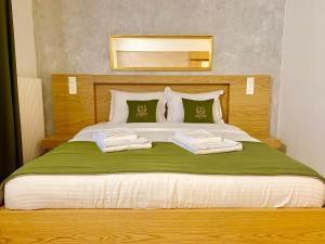 a bedroom with a large bed with green blanket and pillows at Hotel Adore in Romanel-sur-Lausanne