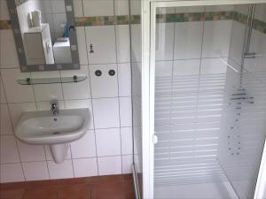 La salle de bains blanche est pourvue d'un lavabo et d'une douche. dans l'établissement Fewo Ostseetraum, à Kühlungsborn