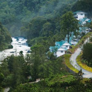 Blick auf einen Fluss mit Häusern auf einem Hügel in der Unterkunft Rivulet Resort in Munnar