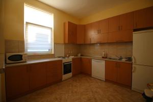a small kitchen with wooden cabinets and a window at Hostel Teresianum in Aleksinac