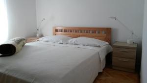 a bedroom with a large bed with two lamps on it at Apartments Janja - terrace sea view in Nečujam