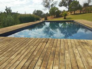 a swimming pool with a wooden deck and blue water at Casa da Osga in Tavira