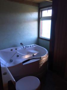 ein Bad mit einer Badewanne, einem WC und einem Fenster in der Unterkunft Oxy in Punta Del Diablo