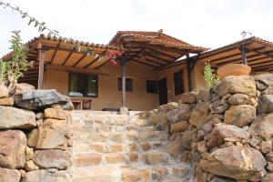 a stone retaining wall in front of a house at Posada El Artesano De Raquira in Ráquira