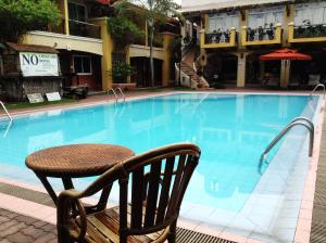 Crown Regency Residences Davao في مدينة دافاو: طاولة وكرسي بجانب مسبح