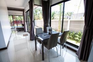 ein Esszimmer mit einem Tisch und Stühlen sowie großen Fenstern in der Unterkunft KP Family Pool Villa Aonang Krabi in Ao Nang Beach