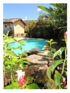 una piscina en un patio con flores en Pousada Fazenda São Luiz en São Luiz do Paraitinga