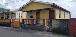una casa gialla con una recinzione rossa davanti di Roseau Hostel & Beach Front Property a Roseau