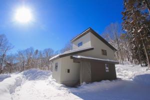 a small house in the snow in the woods at SOLAR CHALETS by Hakuba Hotel Group in Hakuba