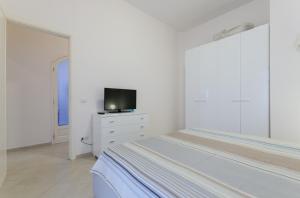 um quarto branco com uma cama e uma televisão numa cómoda em Sunny Beach Home em Rometta Marea