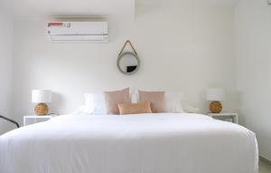 um quarto branco com uma grande cama branca com almofadas em Mucura Hotel & Spa em Cartagena de Indias