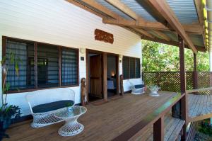 una veranda con sedie e tavolo su una casa di Deco Stop Lodge a Luganville