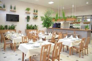 a restaurant with white tables and chairs and plants at Chatky Sázava in Sázava