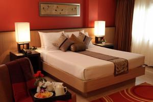 a bedroom with a large bed with red walls at Rose Hotel in Bangkok
