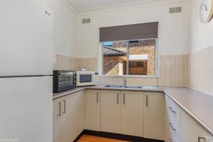 a kitchen with white cabinets and white appliances at Jamaica Holiday Units in Forster