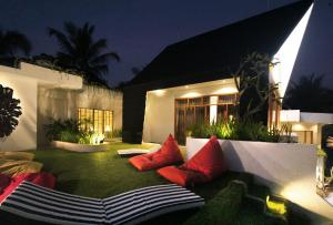 外南梦Onesouth Boutique Hotel Pulau merah的庭院在晚上在草地上提供红色枕头