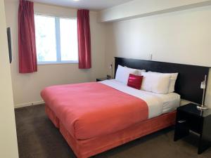 a bedroom with a large bed with red curtains at Salerno Motel Apartments in Christchurch